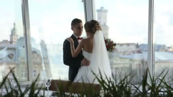 Groom embrasse doucement la belle mariée brune de près. Heureux jeunes mariés. Couple aimant près sur un fond de paysage urbain. L'amour a tourné au ralenti. Caméra en mouvement — Video