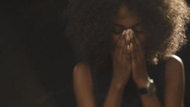 Close up of thoughtful beautiful young african woman on the black background