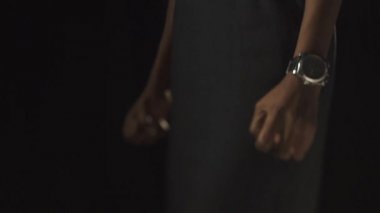 Black african woman compresses fists in despair. Black background.