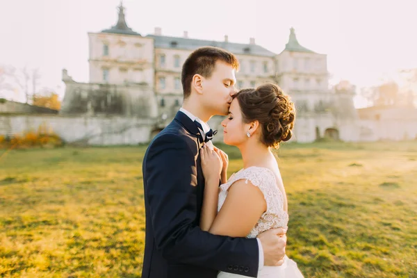 Zbliżenie zdjęcie Happy Groom Całowanie narzeczonych czoło na tle starego zamku — Zdjęcie stockowe