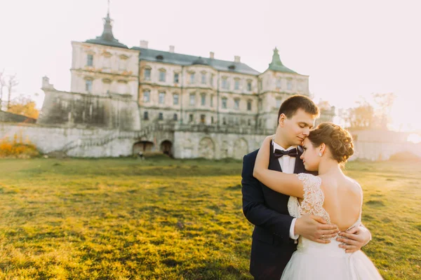 Glückliches Hochzeitspaar umarmt und lächelt sich auf alter Burg an — Stockfoto
