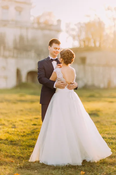 Glückliches Hochzeitspaar umarmt und lächelt sich auf alter Burg an — Stockfoto