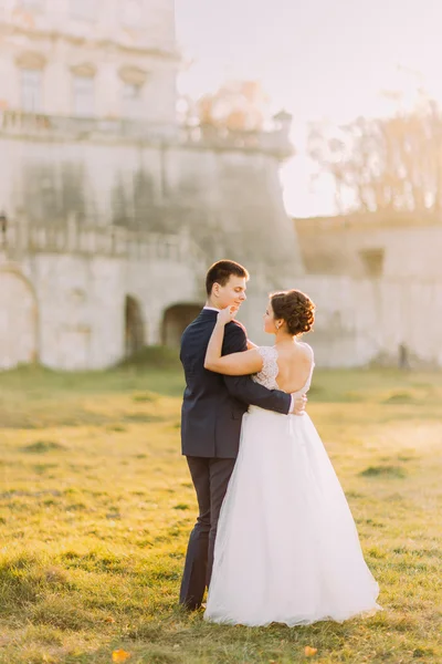 Šťastný Svatební pár objímat a usmívá se navzájem na pozadí starý hrad — Stock fotografie