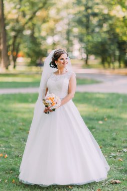 Parkta buket yürüyen beyaz elbiseli güzel genç gelin