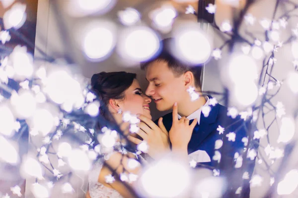 Belo casal abraçando no fundo de guirlandas com luzes — Fotografia de Stock