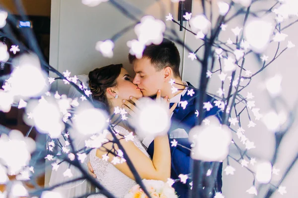 Belo casal se beijando contra o fundo de guirlandas com luzes — Fotografia de Stock