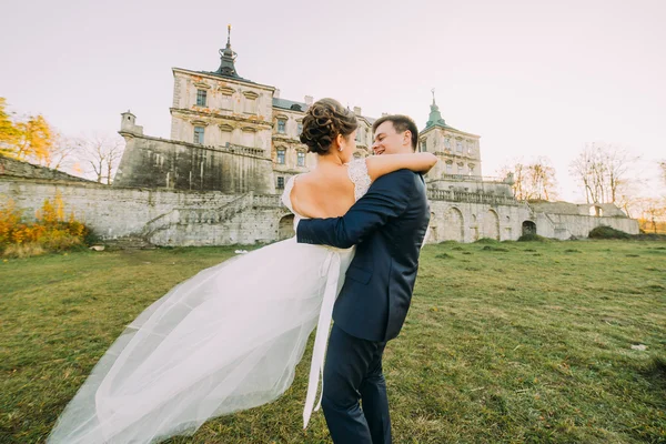 Krásná mladá nevěsta a pohledný ženich tanec venku poblíž staré sídlo při západu slunce — Stock fotografie