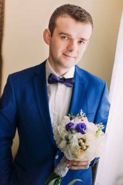 Mavi takım elbise ve kravat bir buket gül ile şirin şık damat