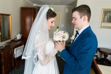 Güzel sevgi dolu düğün çift çiçek buket tutan ve lüks otel iç arka planda öpüşme