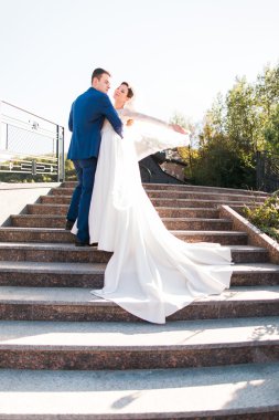 Elegant stylish young couple beautiful bride and groom embracing face-to-face on the stairs