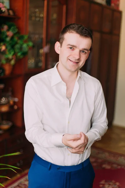 Vita ritratto di giovane uomo d'affari bello sorridente in abito mettere gemelli al chiuso — Foto Stock