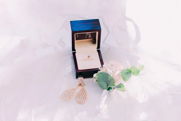 Brincos de noivas e anel de casamento dourado na caixa sobre fundo branco — Fotografia de Stock