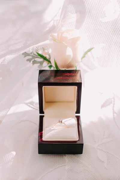 Golden wedding ring in box and rose flowers on the side. — Stock Photo, Image