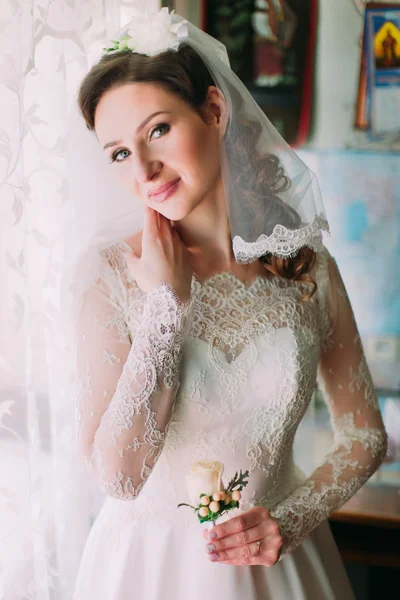 Közelről boldog stílusos menyasszony ruha fehér luxus és fátyol pózol, rózsaszín rózsa, az ablak mellett portréja — Stock Fotó