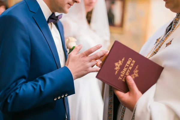 牧师在教堂婚礼上用手指给新郎打上戒指 — 图库照片