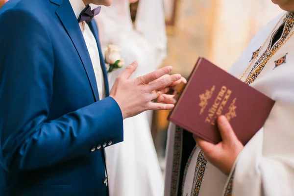 El sacerdote viste anillo en el dedo al novio durante la boda de la iglesia — Foto de Stock