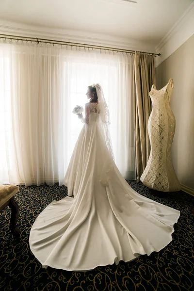 Gorgeous happy luxury stylish bride in white dress and veil near  window on the background of vintage room — ストック写真