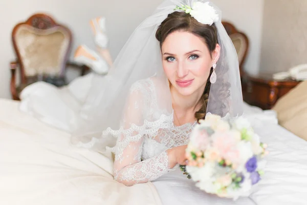 Bonita noiva sorridente na cama olhando para a câmera — Fotografia de Stock