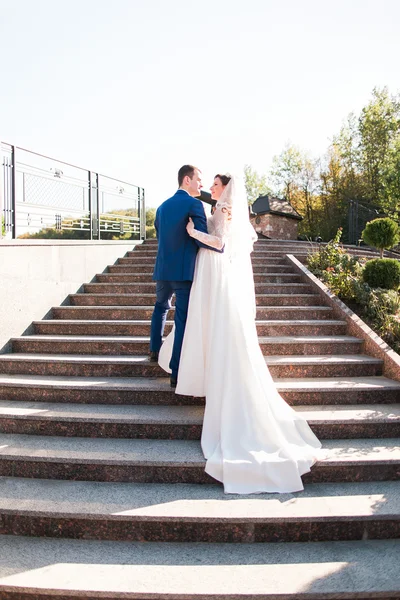 Elegante elegante jovem casal bela noiva e noivo abraçando cara a cara nas escadas — Fotografia de Stock