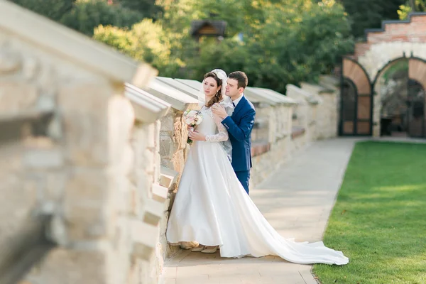 Beau couple de mariage câlin, la mariée tenant un bouquet de fleurs dans sa main — Photo