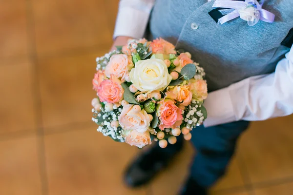 Boy in blue suit holding bridal bouquet of orange roses and white freesias — Stock Fotó