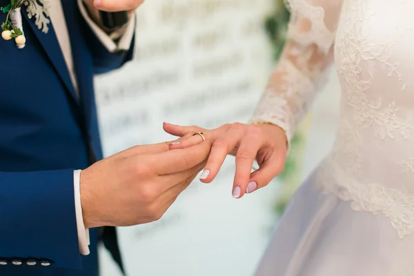 Groom in blue suit putting a wedding ring on brides finger — ストック写真
