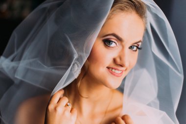 Beautiful smiling blonde bride in make-up and veil close-up