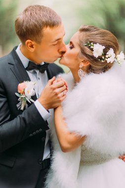 Yakışıklı damat şehvetli onun çekici mutlu gelin açık havada öper, yakın