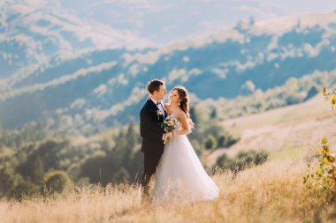 Gelin ve damat çayırda tek başlarına duruyorlar. Bahar akşamı.