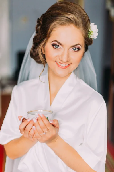 Retrato de bela noiva posando em roupão com copo na manhã do casamento — Fotografia de Stock