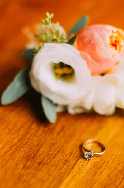 Anel de casamento no fundo de madeira vintage perto do boutonniere de flores e vegetação — Fotografia de Stock