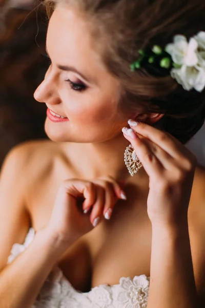Primo piano ritratto di bella sposa in abito da sposa bianco puting su orecchino — Foto Stock