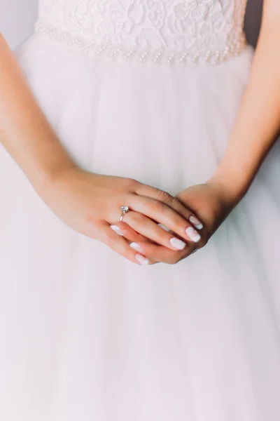 Foto de cerca de hermosas manos de las mujeres con anillo de novia que pone en un vestido blanco —  Fotos de Stock