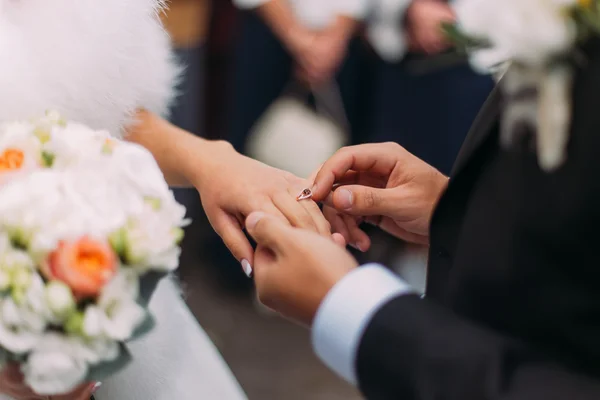 Close-up of elegance groom putting wedding ring on fingers lovely bride — 图库照片