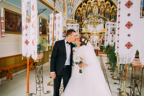 Sposi appena sposati che escono dalla chiesa baciandosi — Foto Stock