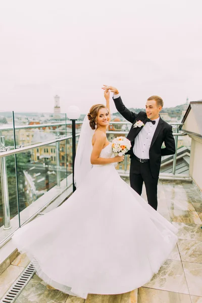 Красива наречена і наречена танцюють на терасі з міським пейзажним фоном — стокове фото