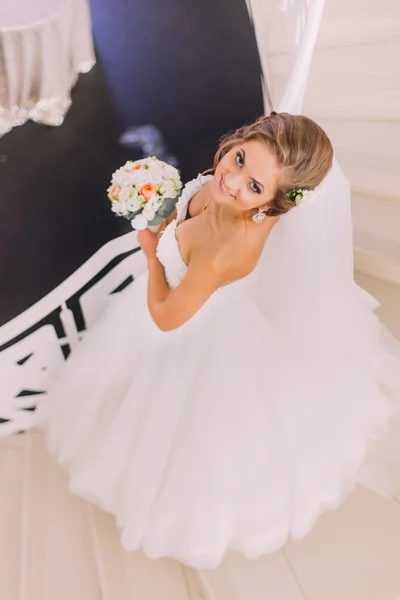 Schöne charmante Braut in einem luxuriösen Kleid mit Blumenstrauß, Blick nach oben, von oben — Stockfoto
