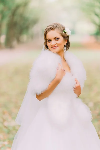 Närbild porträtt av lycklig blond brud i vit klänning och päls boa på Lane på höst parken — Stockfoto