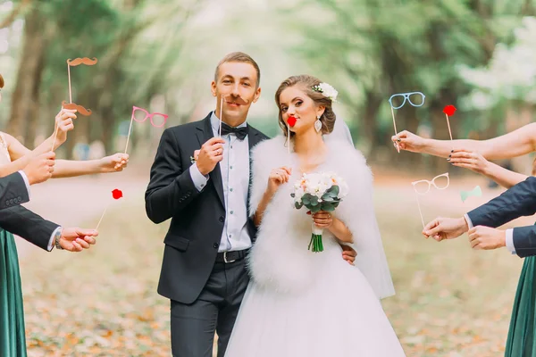 Beautiful married couple attaching to face paper mustache, glasses, bow — Stok fotoğraf