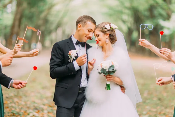 Beautiful married couple attaching to face paper mustache, glasses, bow — Stock Photo, Image