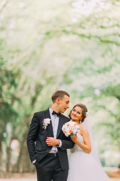 Close-up portrait of happy young wedding couple standing arm-in-arm in park — ストック写真