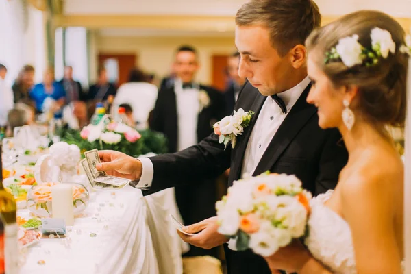 Handsome groom holding redemption of bride on wedding indoors — Zdjęcie stockowe