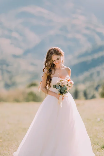 Bella sposa bionda con bouquet da sposa di fiori all'aperto su sfondo di montagna — Foto Stock