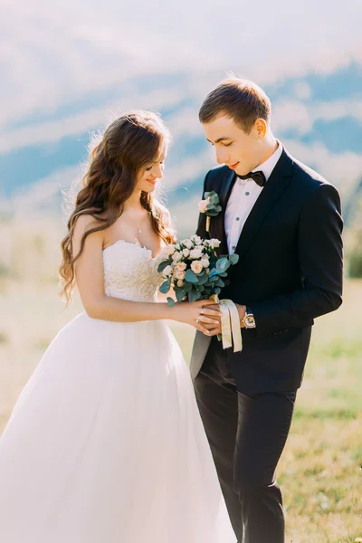 Сказочно счастливая невеста с букетом и стильными груминговыми руками на фоне скал в горах — стоковое фото