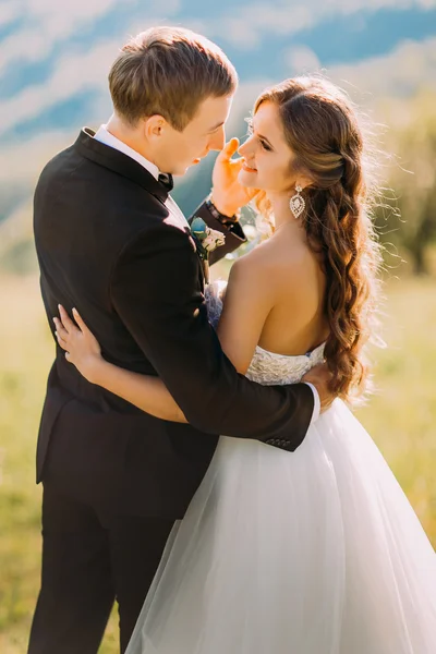 Όμορφος γαμπρός αγγίζει απαλά το πρόσωπο της νύφης του στη φύση — Φωτογραφία Αρχείου