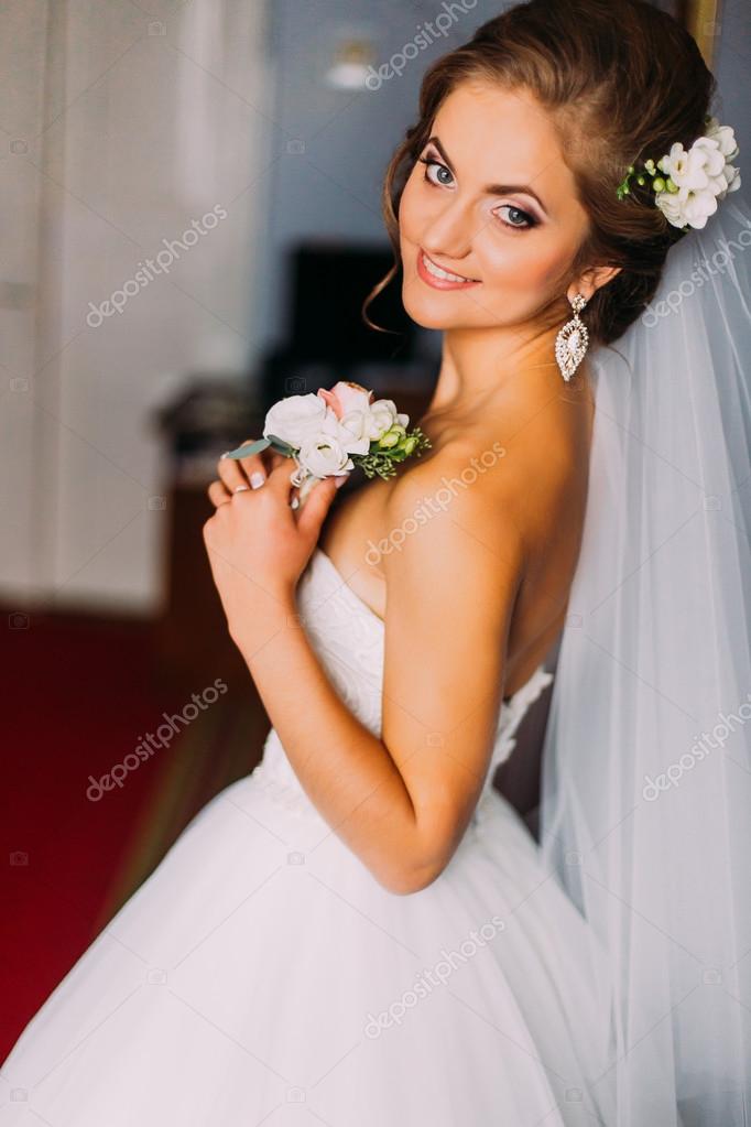 Beauty Bride In Bridal Gown With Hairstyle And Bouquet Indoors