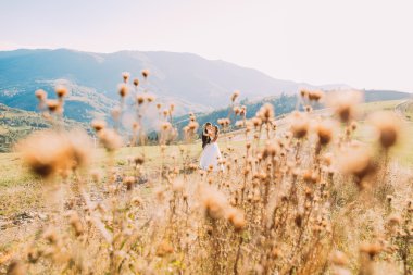 Kır çiçekleri üzerinde arka plan bulanık - damat ve gelin çayırda yürüyüş