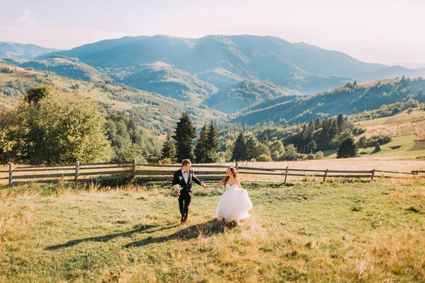 Joven pareja recién casada corriendo en el campo — Foto de Stock