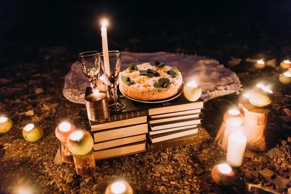 Romantisch diner met kaarsen, cake en wijnglazen aan kust tegen prachtige nacht — Stockfoto