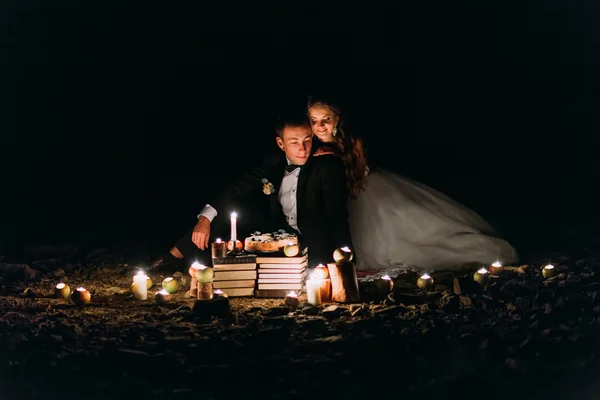 Casal amoroso compartilhar um jantar romântico com velas e bolo na praia, costa contra noite maravilhosa — Fotografia de Stock